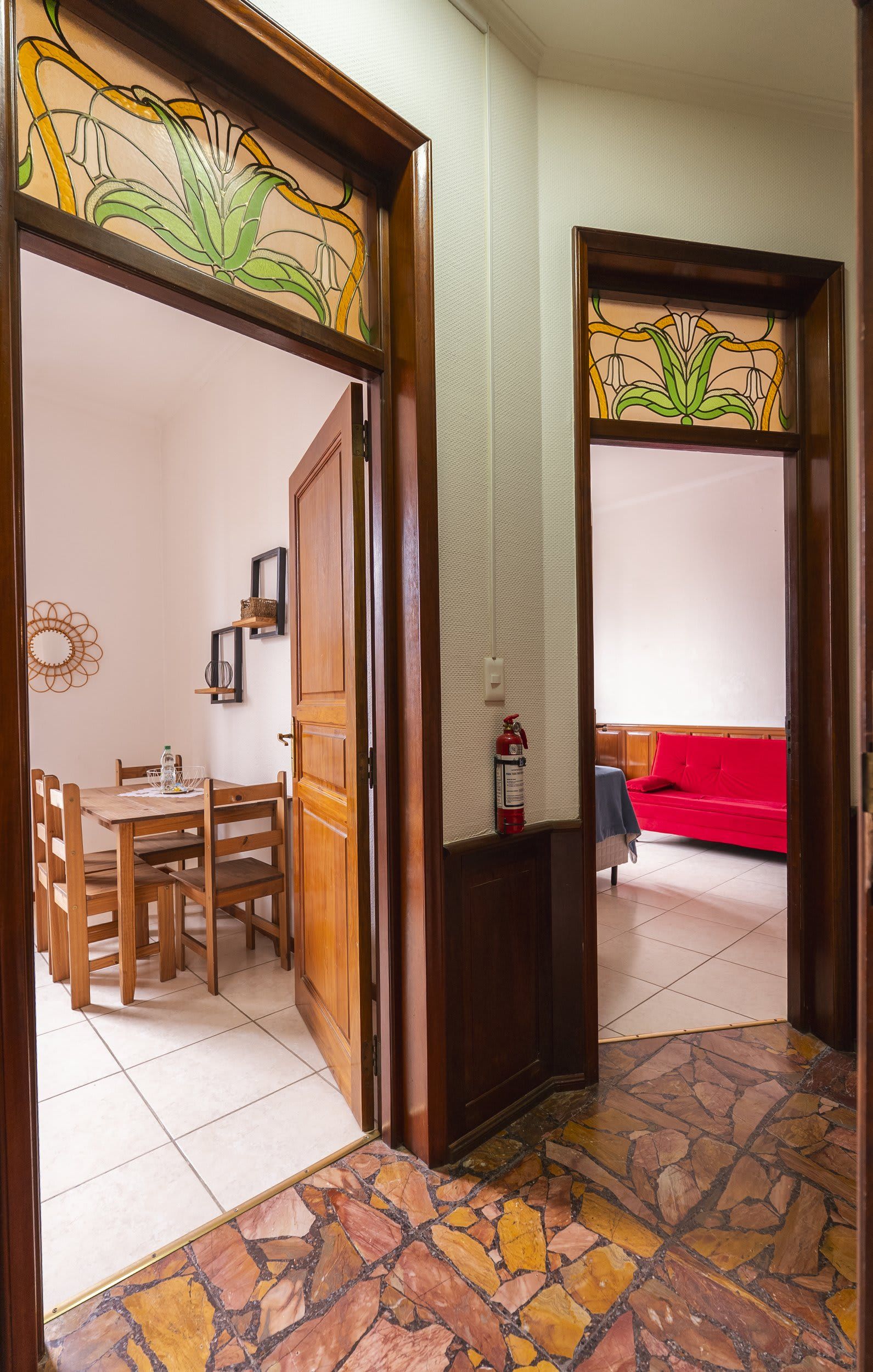 Una habitación con comedor, un sofá rojo y un extintor.