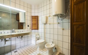 Une salle de bain avec un lavabo en marbre, des toilettes, un bidet et une douche.