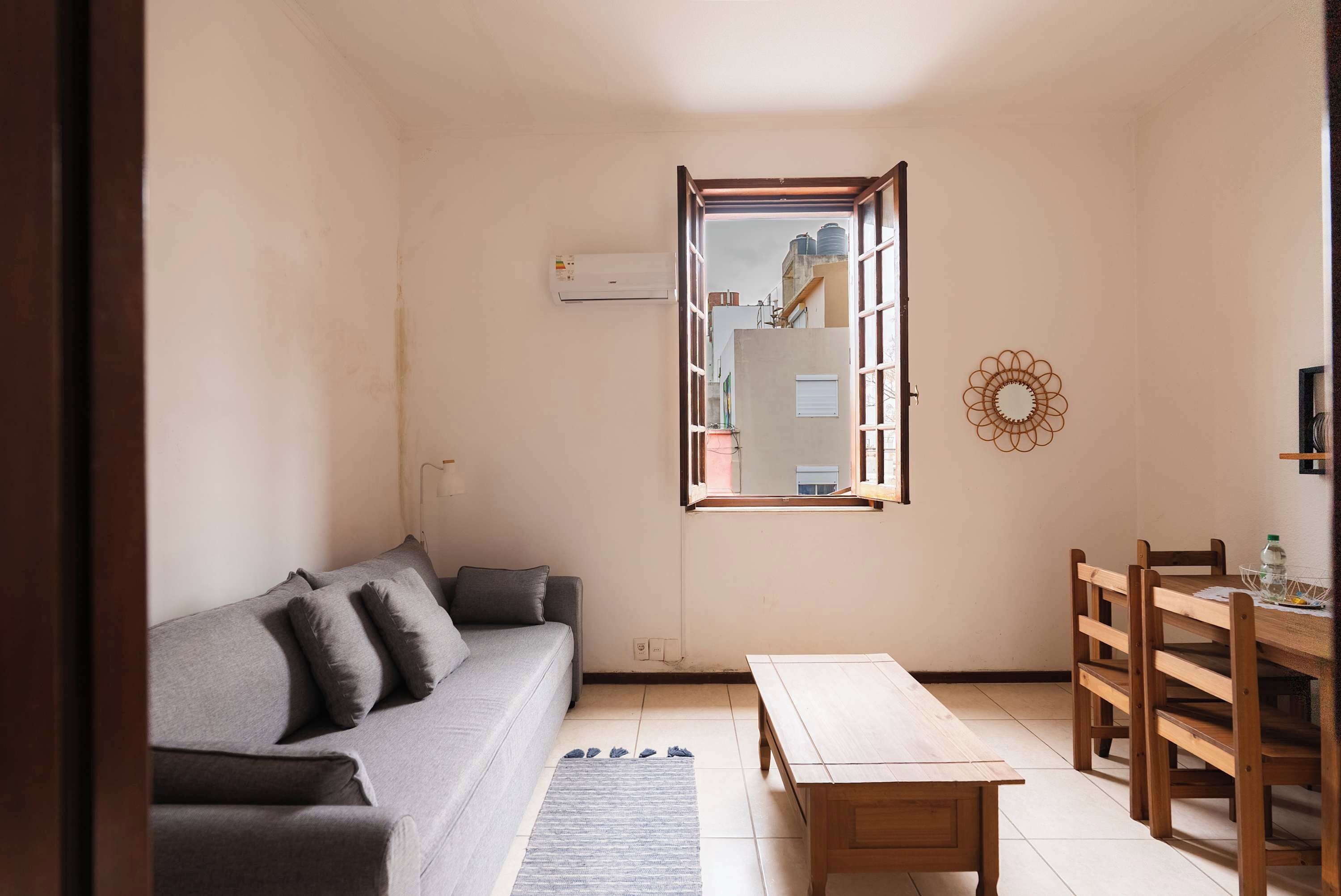 Una sala de estar con un sofá, una mesa de madera y un comedor con sillas.