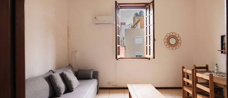 Una sala de estar con un sofá, una mesa de madera y un comedor con sillas.