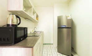 A compact kitchen with a microwave, kettle, and refrigerator.