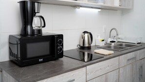 Eine moderne Küche mit einer schwarzen Mikrowelle, einem Kaffeeautomaten und einem Wasserkocher auf der Arbeitsfläche.