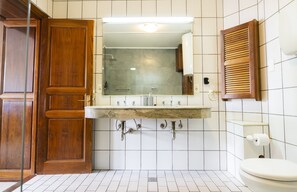 A bathroom with a wooden door, a marble sink, a toilet, and a mirror. - Casa Yacumenza Comfort CoastFlat (Montevideo)