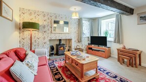 Ein gemütliches Wohnzimmer mit Kamin, Fernseher, Sofa und Couchtisch.