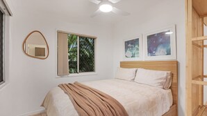 A bedroom with a bed, a ceiling fan, a window with a view of trees, and two framed pictures on the wall. - Unit tucked away in a quiet street (Amity)