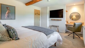 Un dormitorio con cama, televisor, espejo y escritorio.