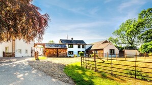 Una propiedad rural con un granero, una casa blanca y un corral cercado.