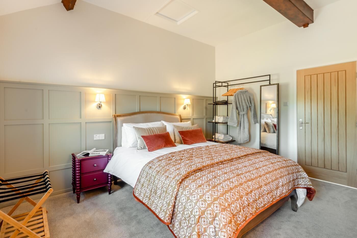 A neatly arranged bedroom with a bed, bedside tables, a wardrobe, and a seating area.
