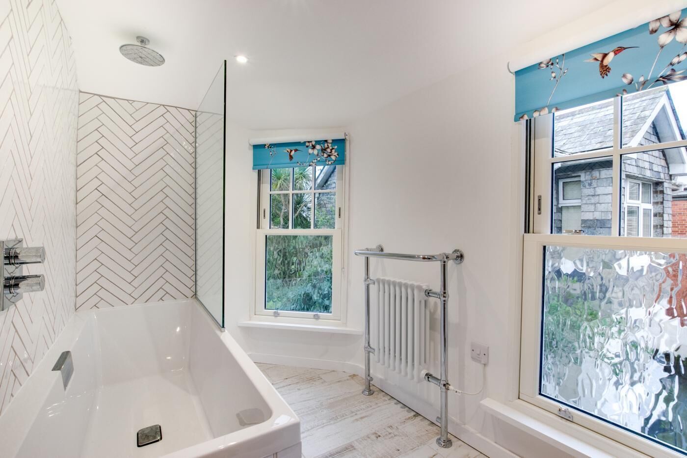 Une salle de bain moderne avec une baignoire sur pieds, une douche en verre et une fenêtre donnant sur un paysage verdoyant.