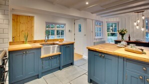 A kitchen with blue cabinets, a wooden countertop, a sink, and a window. - 2 Bed in Padstow (oc-p00821) (Padstow)