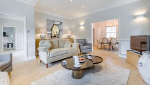 A living room with a sofa, armchairs, a coffee table, and a dining area with a table and chairs. - 4 Bed in Holt (oc-a32207) (Holt)