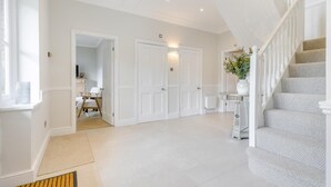 A spacious hallway with a staircase, white doors, and a small table with a vase. - 4 Bed in Holt (oc-a32207) (Holt)