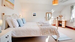 A bedroom with a large bed, bedside tables, a dresser, a mirror, and a painting on the wall. - 4 Bed in South Walsham (oc-2081) (South Walsham)