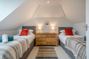 Une chambre avec deux lits, une commode en bois et un tapis à motifs.