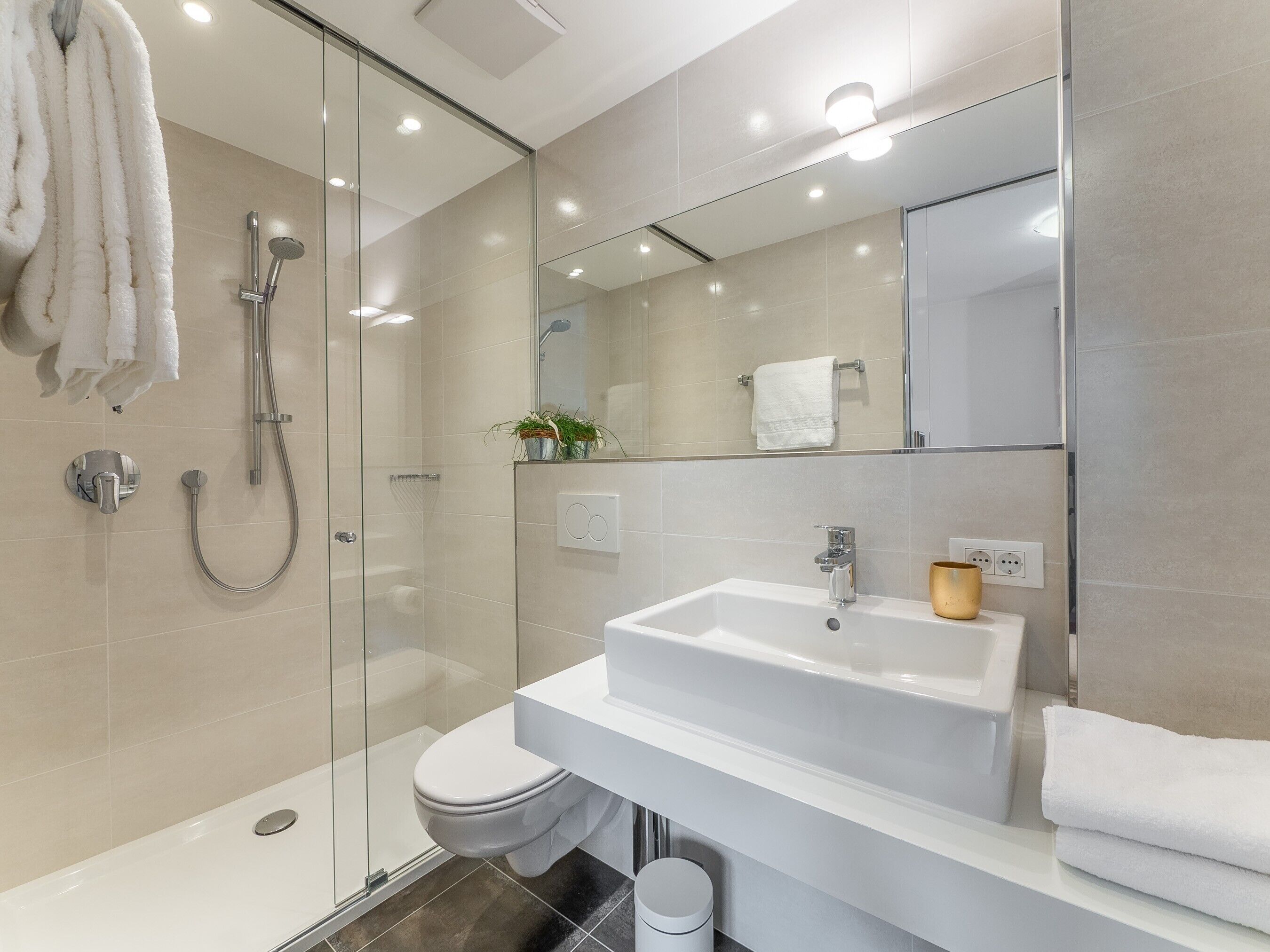 Une salle de bain moderne avec une douche à parois de verre, un lavabo blanc et un miroir.
