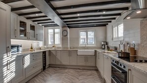 A modern kitchen with herringbone patterned flooring, a built-in oven, and a stainless steel range hood. - 3 Bed in Sandsend (oc-wa241) (Sandsend)