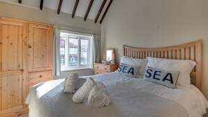 A bedroom with a large bed, wooden headboard, and two pillows with the word "SEA" on them. - 3 Bed in Sandsend (oc-wa241) (Sandsend)