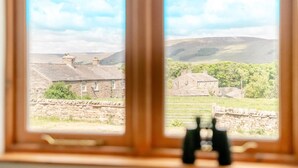 A window with a view of stone buildings and a stone wall, with binoculars on the sill. - 4 Bed in Burtersett (oc-h32270) (Burtersett)