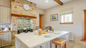 A kitchen with a stone wall, a stove, and a breakfast setup. - 4 Bed in Burtersett (oc-h32270) (Burtersett)