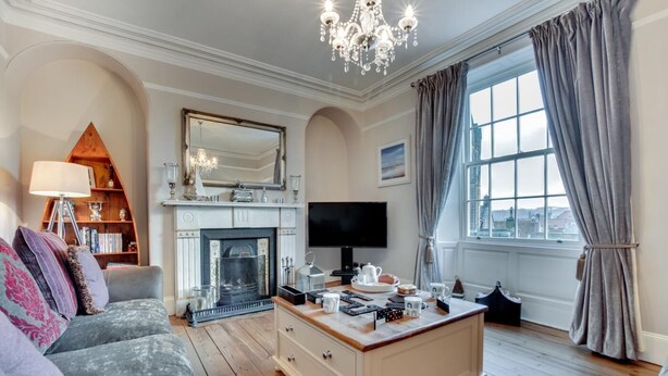 A living room with a fireplace, a television, a coffee table, and a bookshelf. - 4 Bed in Whitby (oc-w474) (Whitby)