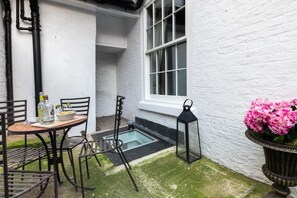 A small outdoor patio with a table and chairs, a black lantern, and a potted plant with pink flowers. - 4 Bed in Whitby (oc-w474) (Whitby)