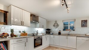 A modern kitchen with white cabinetry, a built-in oven, a microwave, and a sink. - 4 Bed in Whitby (oc-w474) (Whitby)