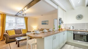Una cocina moderna con una isla central, un área de comedor con sofá y mesa, y vistas de la ciudad a través de grandes ventanales.