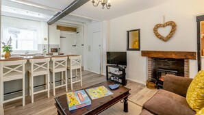Una sala de estar moderna con chimenea, un comedor con mesa y sillas, y una cocina visible al fondo.