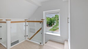 Une pièce dotée d’une porte vitrée donnant sur un escalier, d’une fenêtre offrant une vue sur la verdure et d’un plafond blanc.