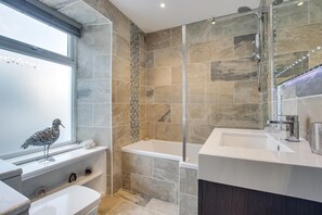 Une salle de bain moderne dotée d’une grande fenêtre, d’une douche et d’une baignoire.