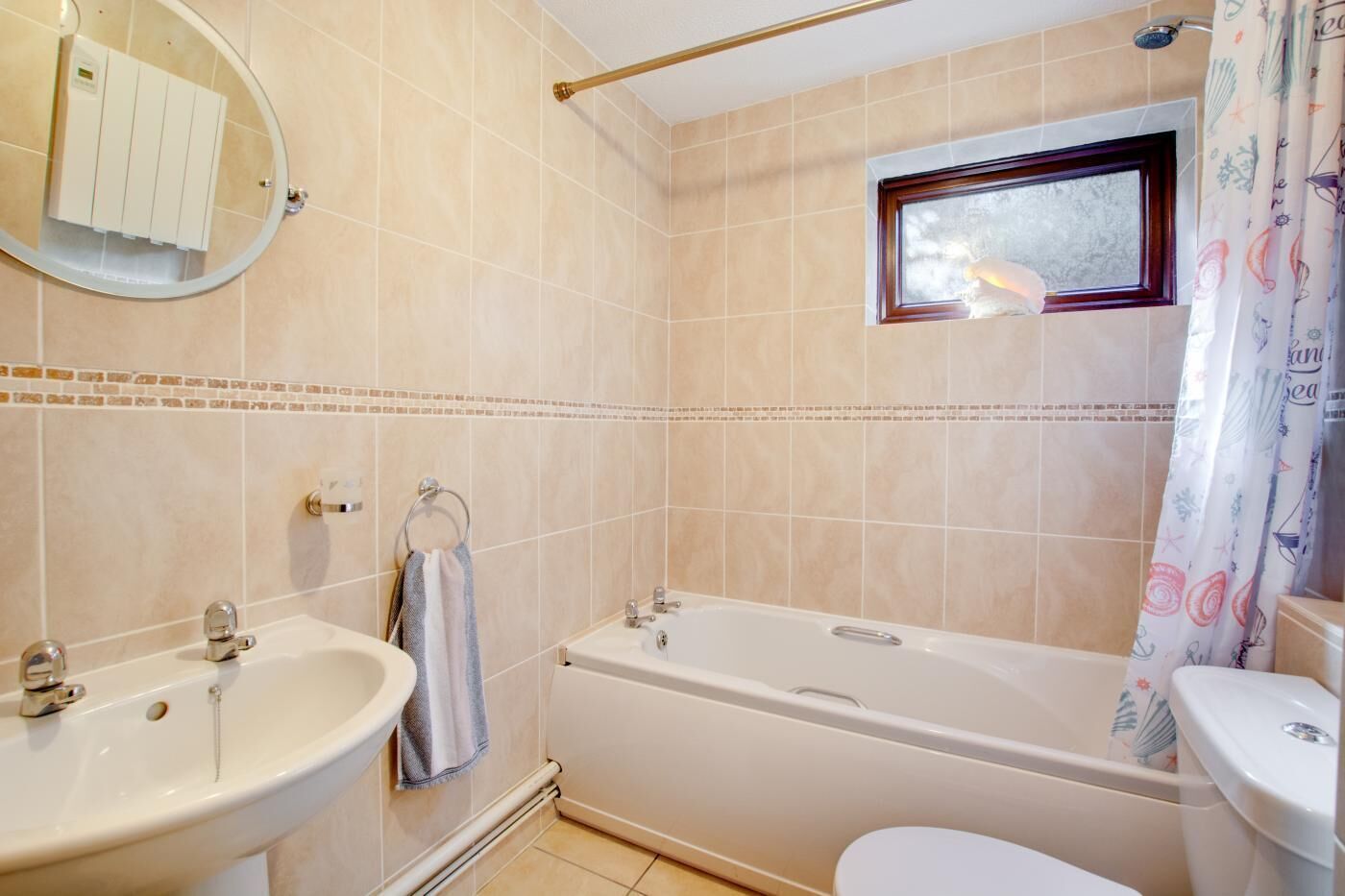 Een badkamer met een bad, een wastafel, een toilet, een raam en een handdoekhouder.