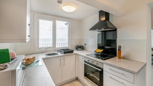 Una cocina moderna con estufa, horno y un amplio ventanal con vista al mar.