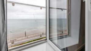 A view from a window overlooking a beach with a fence and a flag. - 3 Bed in Bridlington (oc-o32293) (Bridlington)