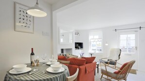 Ein Essbereich mit gestreifter Tischdecke, einer Weinflasche und weißen Tellern.