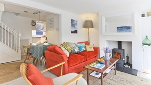 Ein Wohnzimmer mit einem roten Sofa, Holzstühlen, einem Couchtisch und einem Kamin.