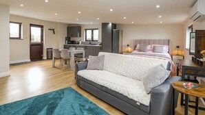 Um apartamento moderno com cozinha compacta, sala de jantar, sala de estar com sofá e quarto com cama.