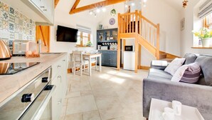 Una cocina moderna con comedor, una sala de estar con sofá y una escalera que conduce a un nivel superior.