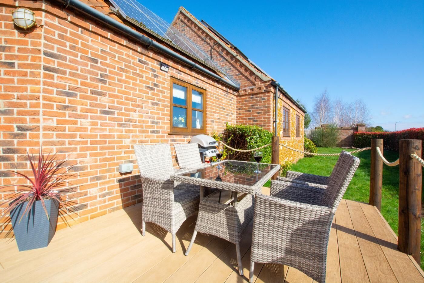 A brick house with a patio, outdoor furniture, and a barbecue grill.