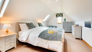 Un dormitorio con cama, mesita de noche, lámpara, cómoda y televisor.