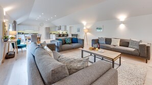 Ein modernes Wohnzimmer mit einer Sofagarnitur, einem Couchtisch und einem Essbereich mit Stühlen.