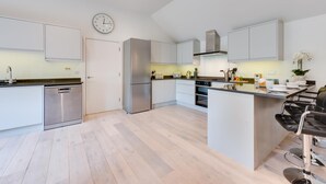 Eine moderne Küche mit Edelstahlgeräten, einer zentralen Kochinsel und einem Essbereich mit Barhocker.