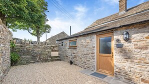 A stone building with a wooden door, a gravel courtyard, and a stone wall. - 2 Bed in Nenthead (oc-s32235) (Alston Moor)