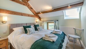 A bedroom with a bed, pillows, a green blanket, a chair, and a window. - 2 Bed in Nenthead (oc-s32235) (Alston Moor)