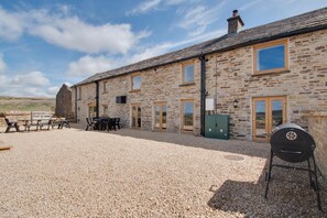 A stone building with a gravel patio, outdoor seating, and a barbecue grill. - 5 Bed in Nenthead (oc-f32234) (Alston Moor)