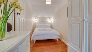 A narrow hallway leading to a bed with a white headboard and two bedside lamps. - 3 Bed in St Ives (oc-vgn25) (St Ives)