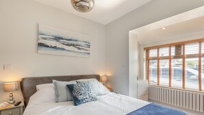 A bedroom with a bed, bedside tables, a painting, and a window with blinds. - 4 Bed in Berrow (oc-h32250) (Berrow)