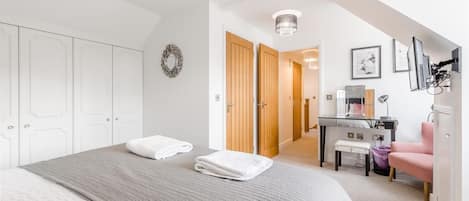 A bedroom with a bed, a desk, a chair, and a wardrobe.
