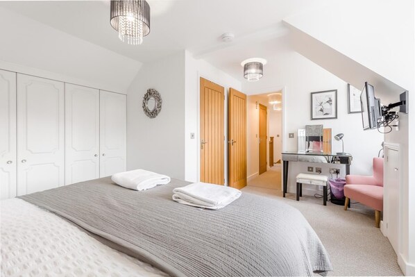 A bedroom with a bed, a desk, a chair, and a wardrobe. - 3 Bed in Old Hunstanton (oc-2104) (Hunstanton)