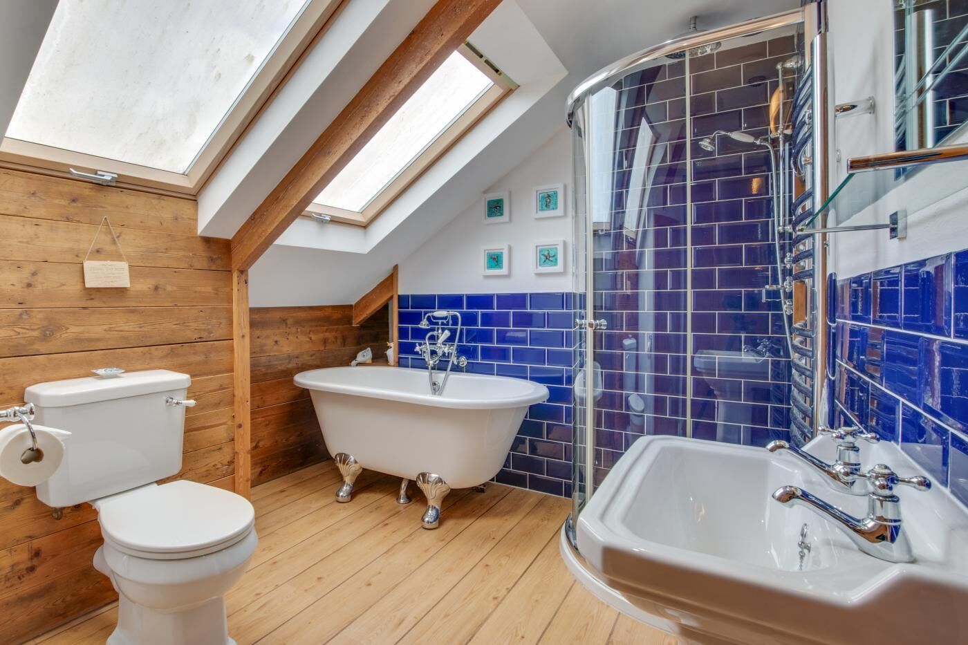 A bathroom with a skylight, a freestanding bathtub, a toilet, and a sink.