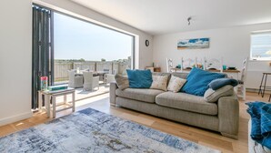 A living room with a sofa, a coffee table, a rug, and a dining area with chairs and a table. - 3 Bed in Woolacombe (oc-c32222) (Woolacombe)